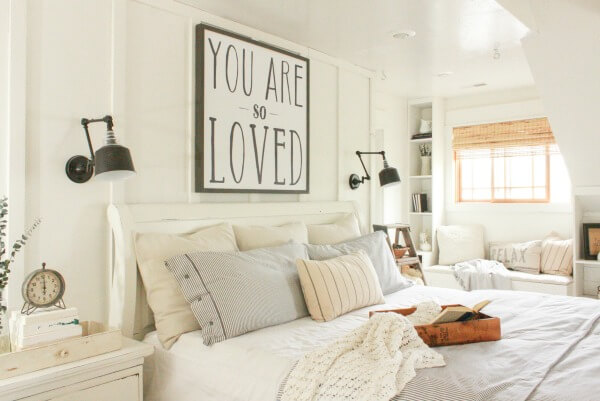 To make a small room look bigger, this all-white farmhouse bedroom utilized smart storage with built-in bookcases and a window seat.