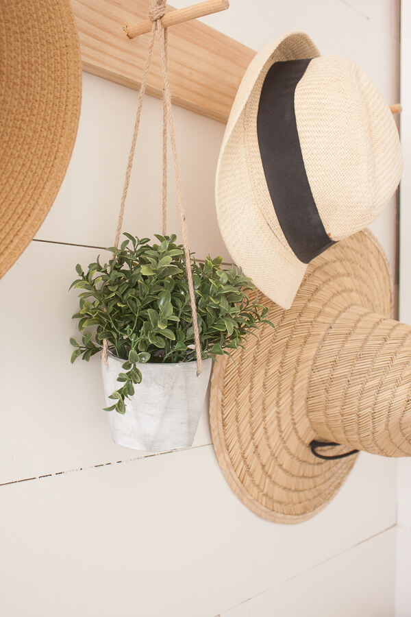 Shiplap, a vintage church pew, straw hats, an adorable dog pillow and a custom piece of artwork makes this spring entryway decor stand out!