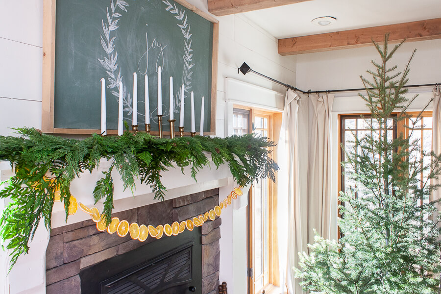 Scandinavian Christmas mantel with dried orange garland, fresh greenery, and amazing vintage Baldwin brass candlesticks!