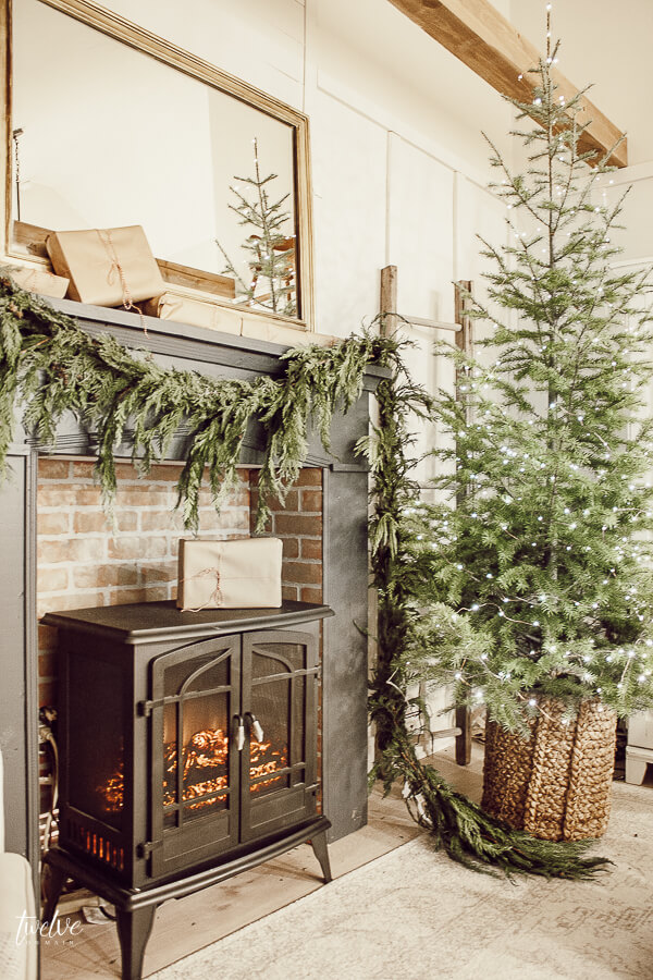 Farmhouse style Christmas bedroom decor, with a beautiful faux brick fireplace, mantel painted in Farrow and Ball Downpipe, real cedar garland, a golden mirror, and so much more.  Such a cozy space full of elegant and effortless Christmas decor!
