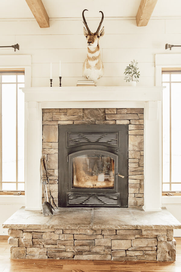 Beautiful fireplace with an Antelope mount, mini olive tree, and a few black candlesticks.