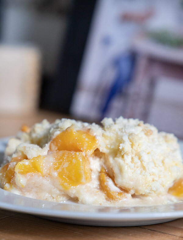 The ultimate combination of tart peaches, tangy cream cheese, and sweet white cake. This cream cheese peach cobbler is so delicious and easy to make! It is the perfect peach dessert!