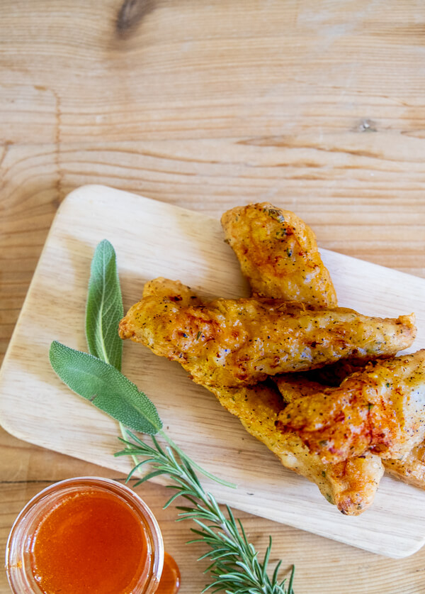 The crispiest fried chicken recipe ever! It has a flavorful herb infused batter and its topped off with a honey Sriracha sauce that is sweet and spicy!