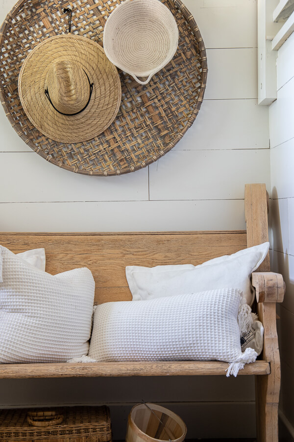Fall decor ideas including my wooden church pew in the entry with baskets on the wall, topped with straw hats and rope baskets.  White pillows top of the vintage church pew and a basket of pears adds a touch of color to this neutral fall entryway.