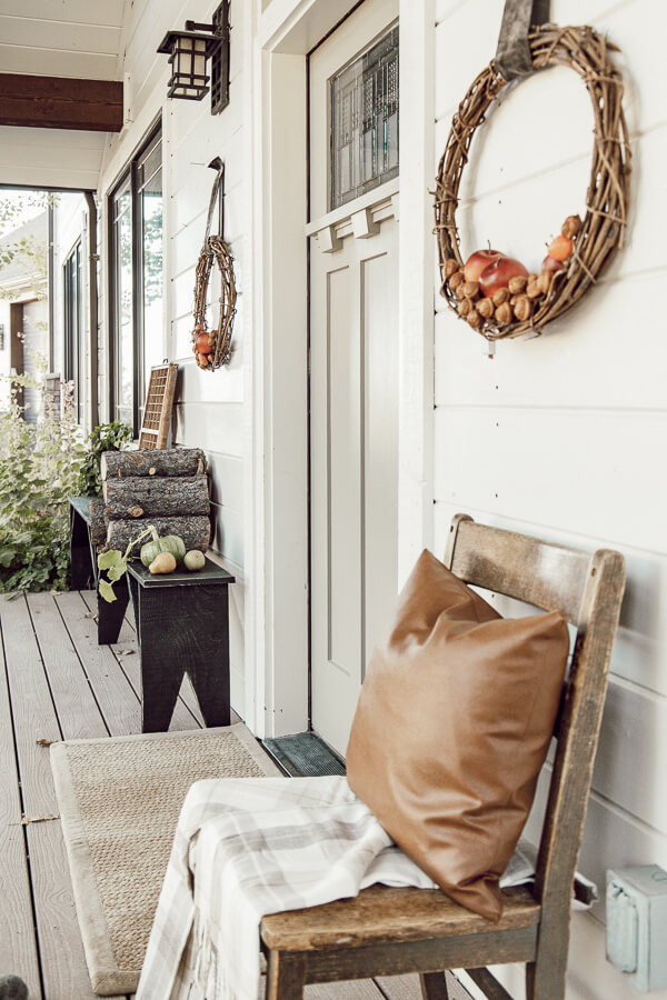 Simple porch decor for fall. Stacks of firewood, handmade wreaths, and a simple pumpkin or two. Neutral fall decor on the porch.