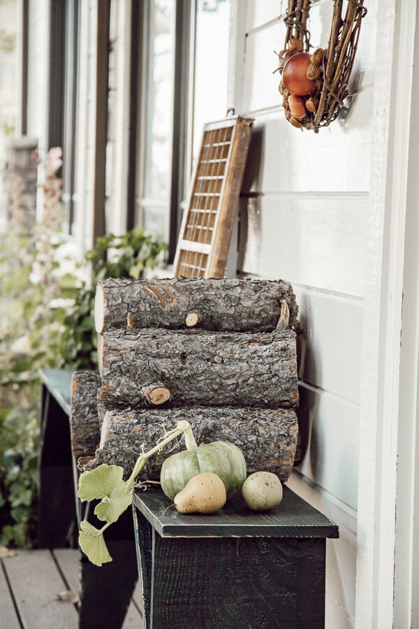 Simple porch decor for fall. Stacks of firewood, handmade wreaths, and a simple pumpkin or two. Neutral fall decor on the porch.