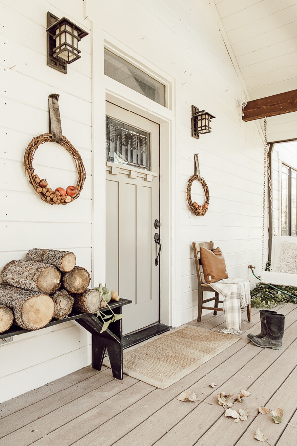 Welcome to my home for fall. My porch is decked out with simple fall items. A black primitive bench, handmade apple and walnut fall wreaths, stacks of firewood, and baskets of leaves. A lone pumpkin rounds out the decor.