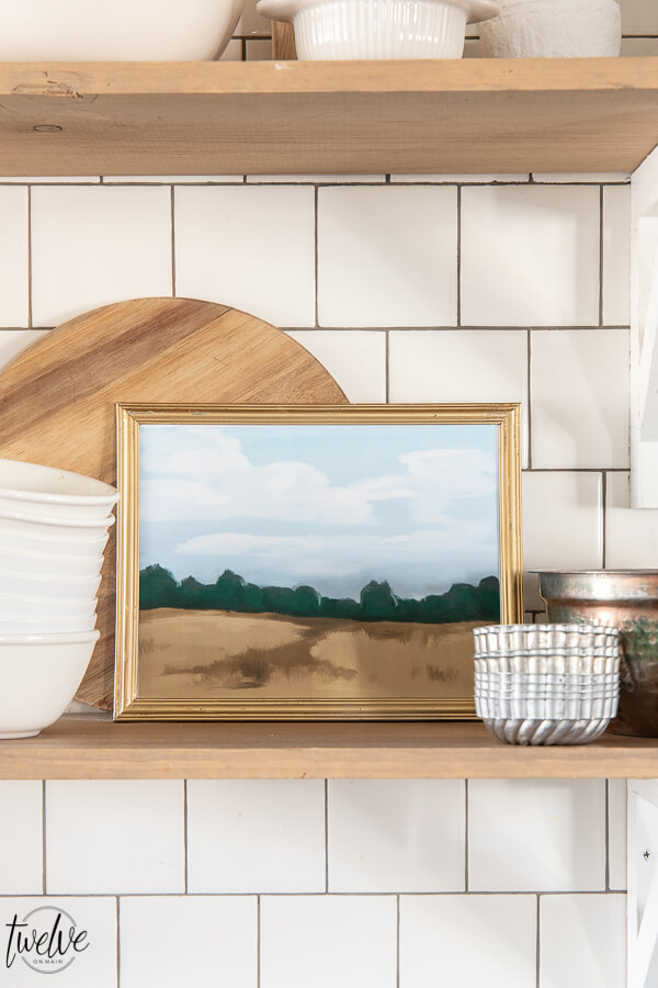 Printable art in the kitchen, on open shelving, styled with butcher blocks cutting boards, copper bowls, and brick style subway tile backsplash
