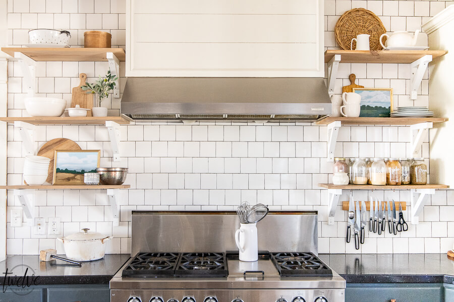 Printable art in the kitchen, on open shelving, styled with butcher blocks cutting boards, copper bowls, and brick style subway tile backsplash