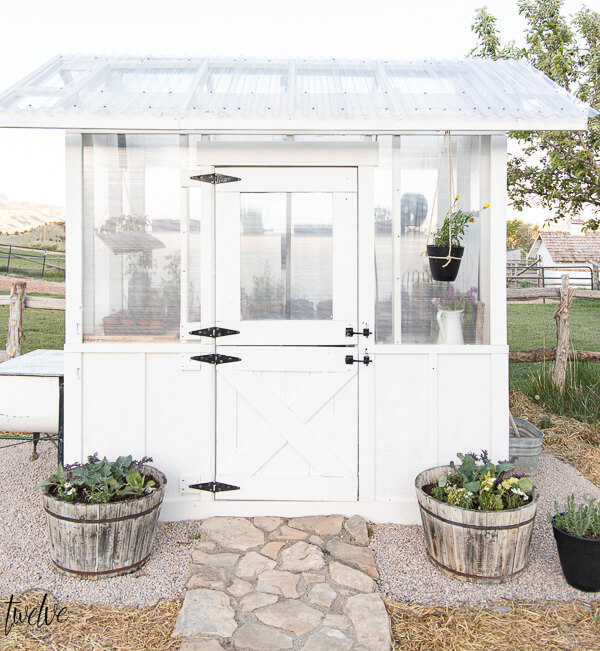 Our DIY greenhouse reveal! Check out all the amazing details of this simple, but gorgeous greenhouse design. A dutch door, board and batten, a gorgeous black light fixture and so much more!