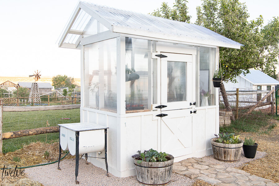 Stylish and functional DIY greenhouse design complete with a dutch door that serves as the window, an outdoor washing station, rustic wood shelving and so much more!