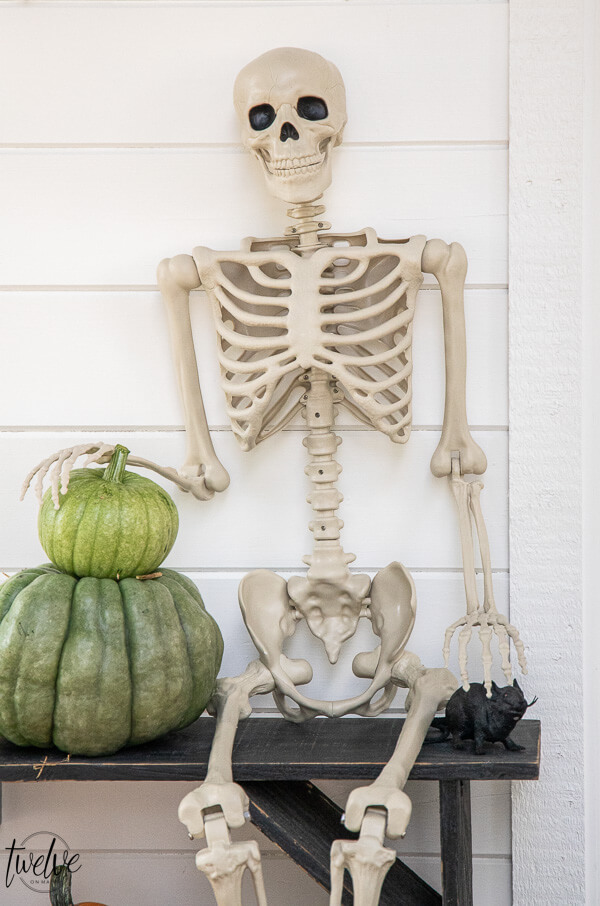 Affordable Halloween porch ideas including paper bats, real pumpkins, and a spooky posable skeleton!