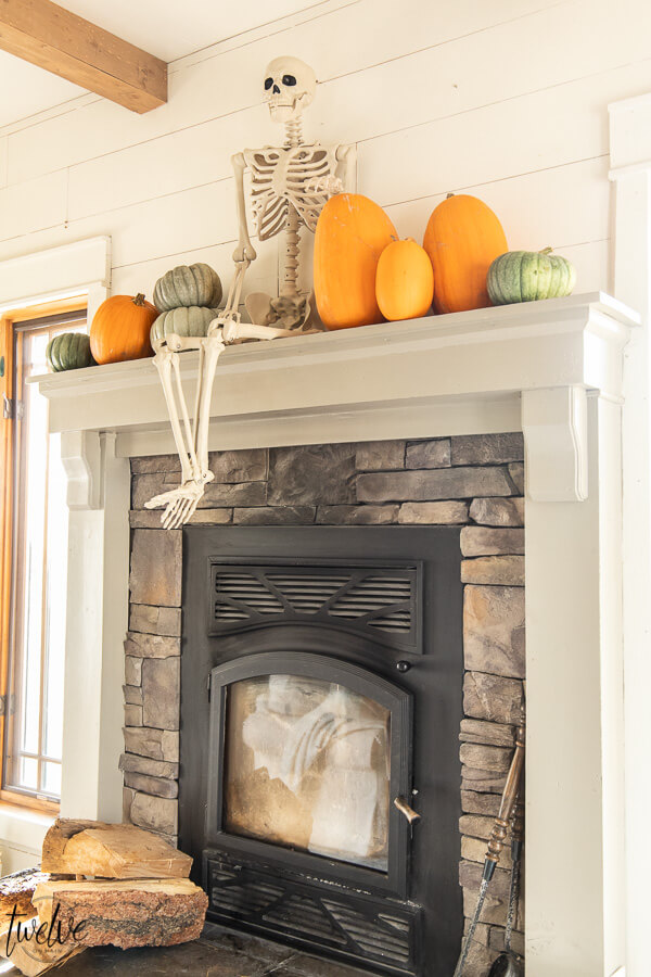 What a fun way to decorate for Halloween! Check out this amazingly simple and conversation starter Halloween mantel!  This is so fun!  A full sized posable skeleton along with some real pumpkins are the perfect Halloween mantel accessories!
