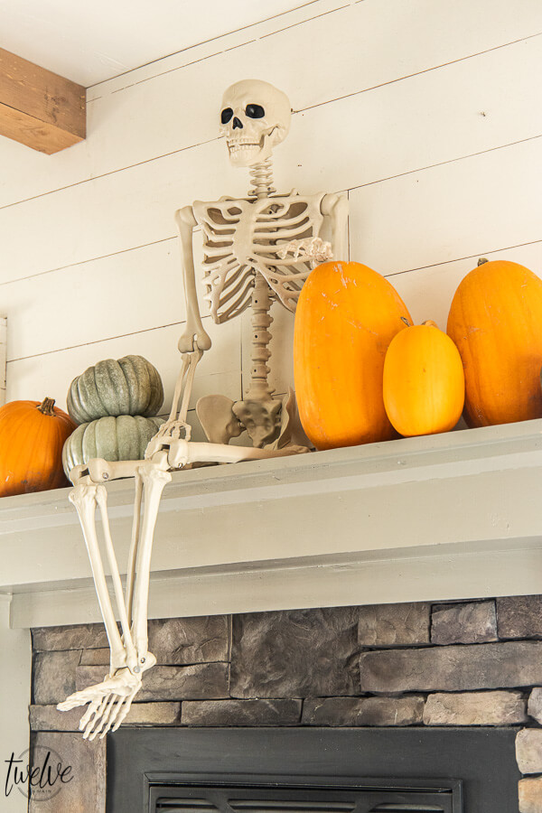 What a fun way to decorate for Halloween! Check out this amazingly simple and conversation starter Halloween mantel!  This is so fun!  A full sized posable skeleton along with some real pumpkins are the perfect Halloween mantel accessories!