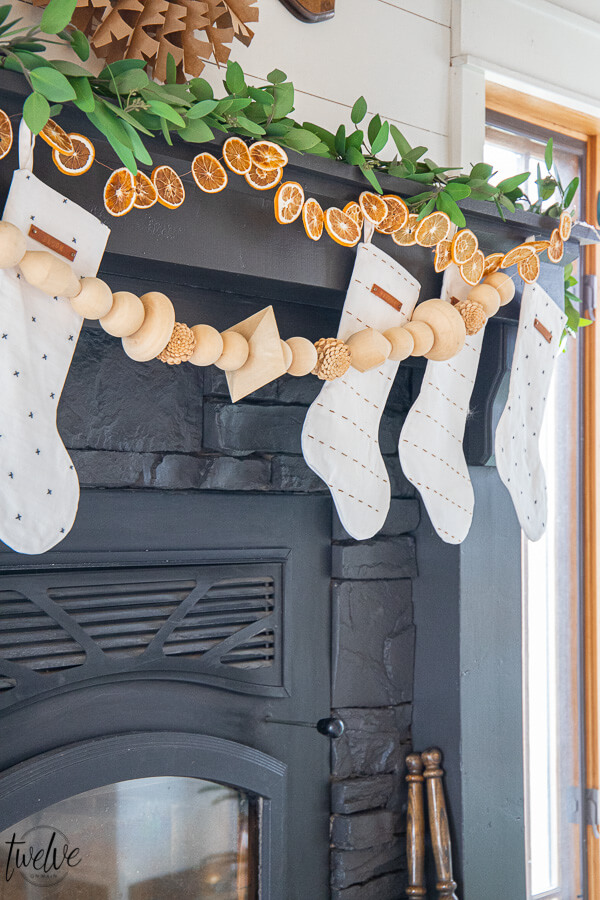 Gorgeous boho/Scandinavian holiday mantel complete with eucalyptus, dried orange slices, and wooden bead garland.