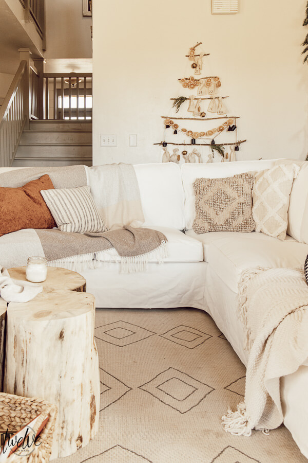 Get some cozy Christmas living room decor inspiration with wood stump coffee tables, cedar garland, a unique advent calendar, white Ektorp sectional, gorgeous painted black fireplace and so much more.