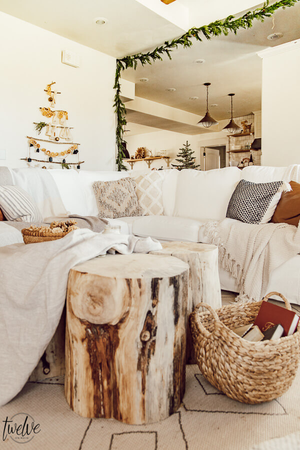 Get some cozy Christmas living room decor inspiration with wood stump coffee tables, cedar garland, a unique advent calendar, white Ektorp sectional, gorgeous painted black fireplace and so much more.
