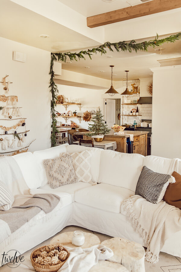 Get some cozy Christmas living room decor inspiration with wood stump coffee tables, cedar garland, a unique advent calendar, white Ektorp sectional, gorgeous painted black fireplace and so much more.