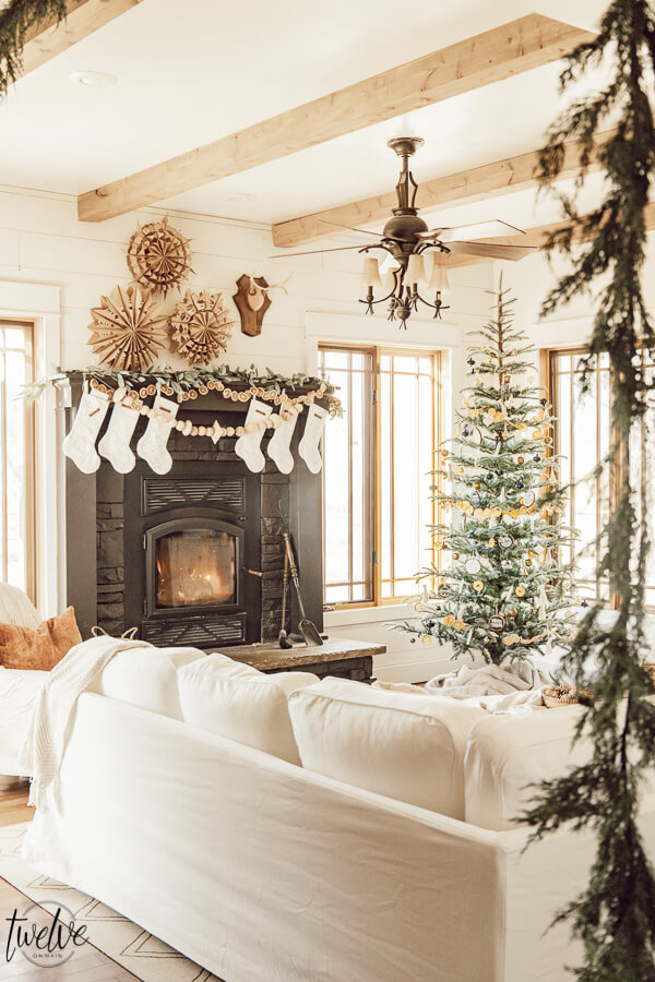 Get some cozy Christmas living room decor inspiration with wood stump coffee tables, cedar garland, a unique advent calendar, white Ektorp sectional, gorgeous painted black fireplace and so much more.