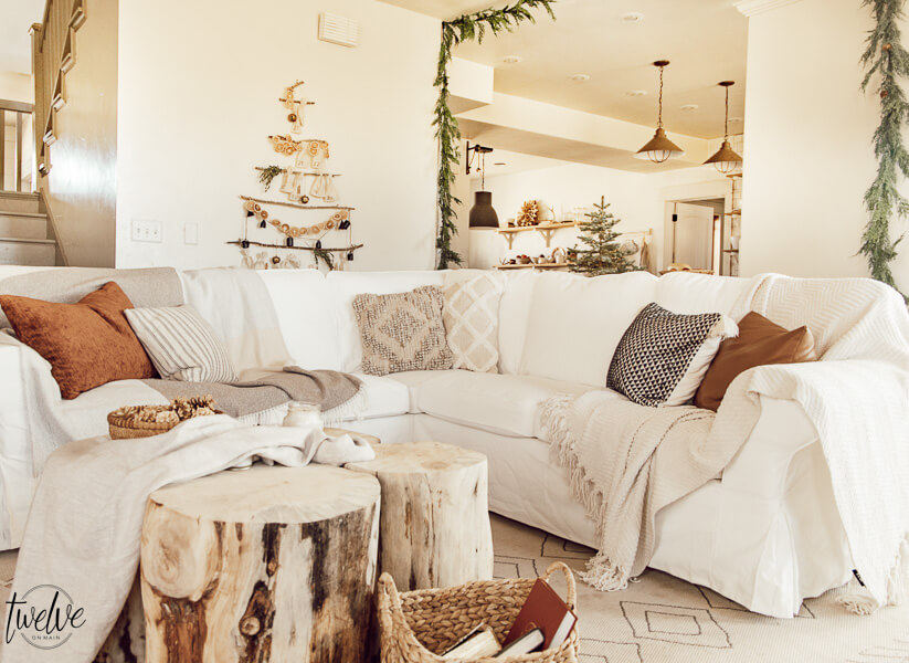 Get some cozy Christmas living room decor inspiration with wood stump coffee tables, cedar garland, a unique advent calendar, white Ektorp sectional, gorgeous painted black fireplace and so much more.