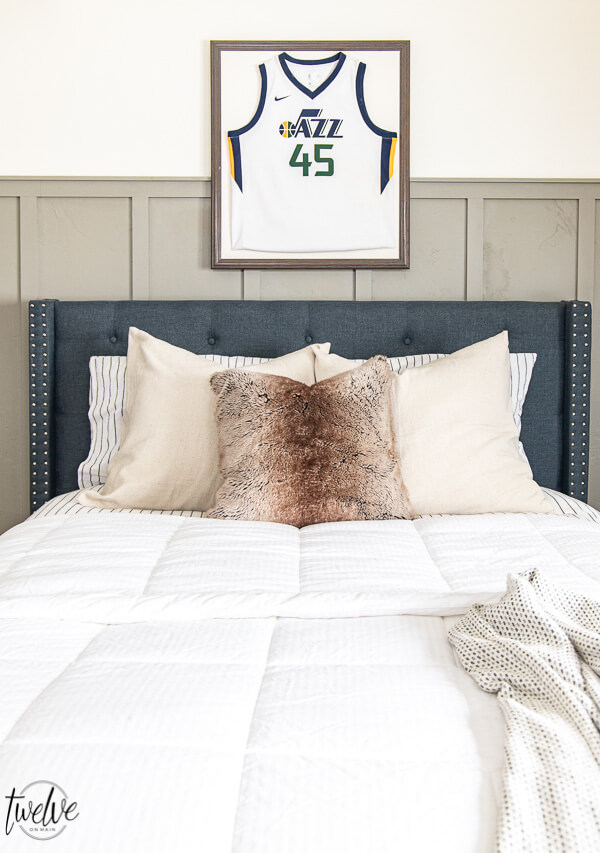 Teen bedroom with board and batten and a Jazz jersey wall art above the upholstered bed.