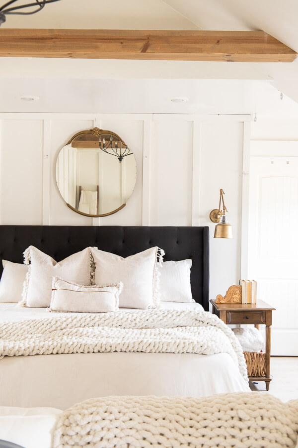 Gorgeous master bedroom with cozy bed linens, antique side tables, and mirror. A bed flanked with wall lamps refinished with Rub-N-Buff Antique Gold finish.