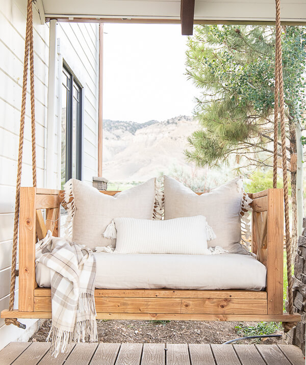 Make this easy DIY porch swing using these easy to follow building plans. This is stylish, and so cozy! Make sure to check it out!