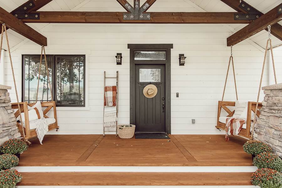 Simple fall front porch decor using items that will bring you from the summer to fall without spending a lot of money! An old ladder serves as a blanket ladder, a hat as a wreath, take advantage of thee falling leaves and use them in your porch decor.