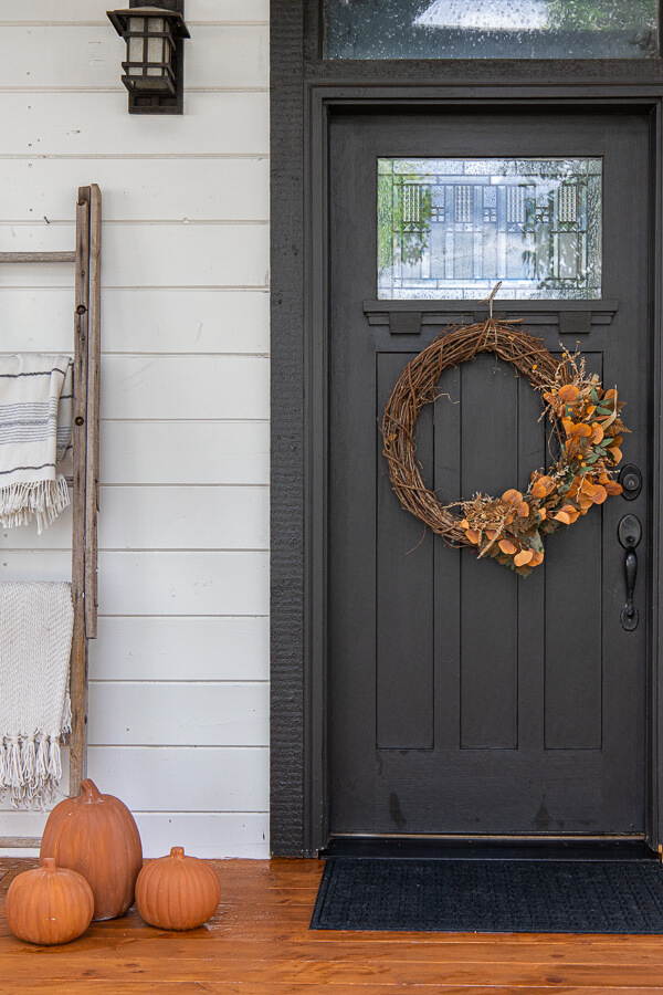 Fall porch with terra cotta pumpkins, and a gorgeous fall eucalyptus wreath.